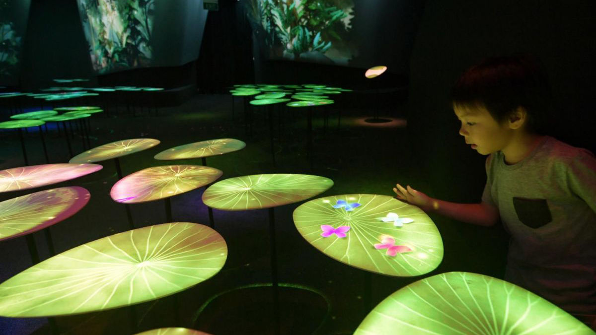 Ein Kind, das mit der Schmetterlingsinstallation im Garden of Harmony im Changi Experience Studio interagiert